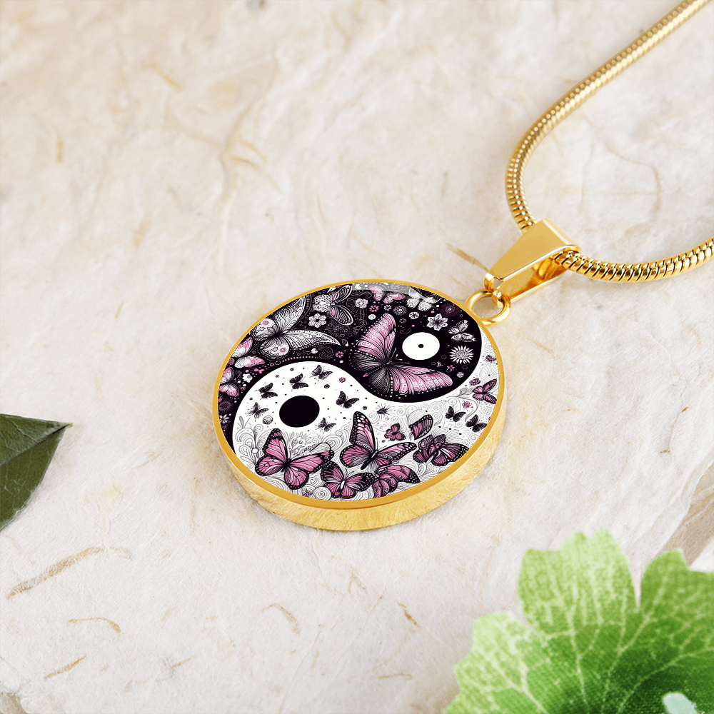 Gold necklace with a round pendant featuring a yin-yang symbol filled with butterfly designs in shades of pink and black.