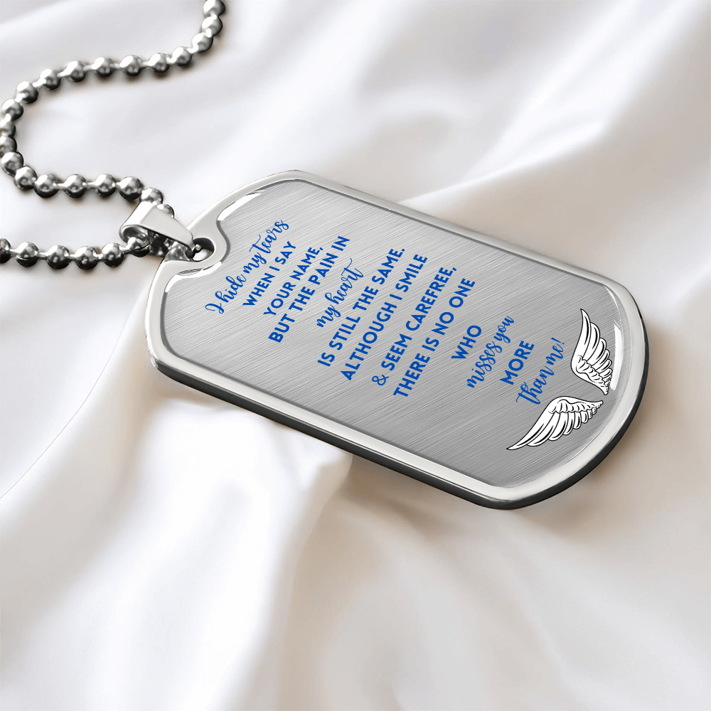 Silver memorial dog tag necklace with engraved blue text and wing design on satin background.
