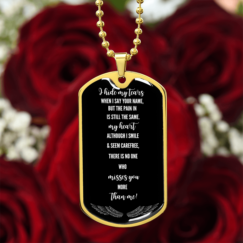 Gold military dog tag necklace with engraved grief poem on black background, hanging over red roses.