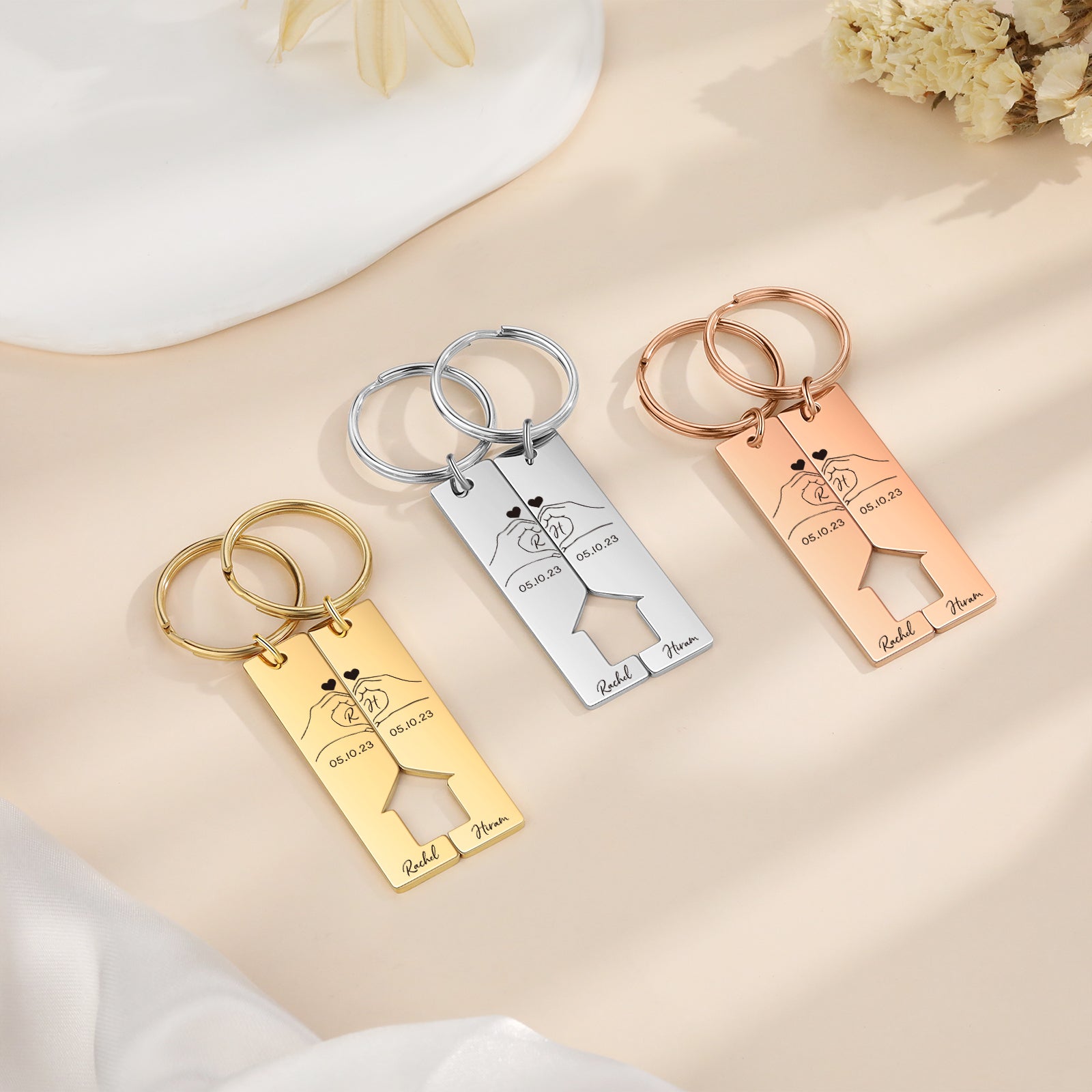 Set of three personalized rectangular stainless steel keychains with engraved stick figure couples and heart details in.