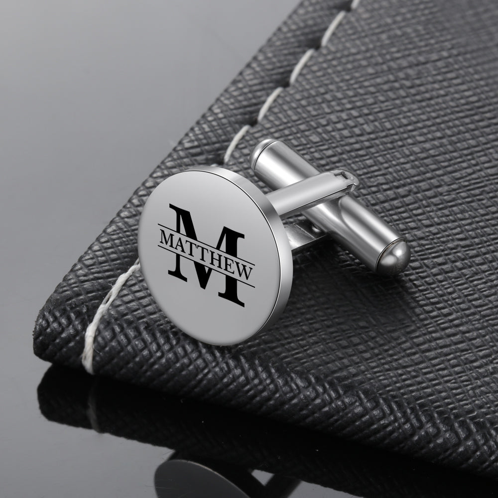 Round silver stainless steel cufflinks with engraved black letter M and name Matthew in serif font.