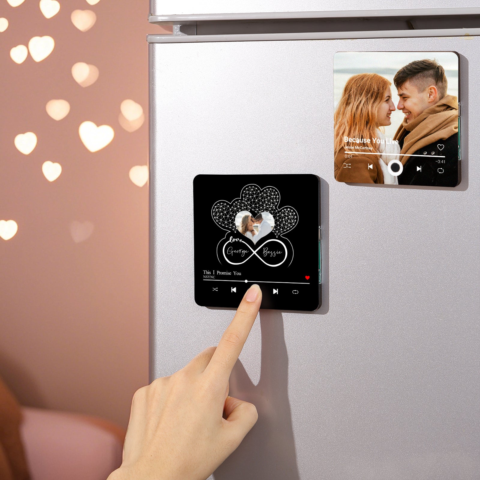 Close-up shot of two personalized magnets on a refrigerator: one displaying a couple looking at each other with a song title, "Because You Live" by Jesse McCartney, and the other with a couple inside a heart-shaped design with names and the song "This I Promise You" by NSYNC.