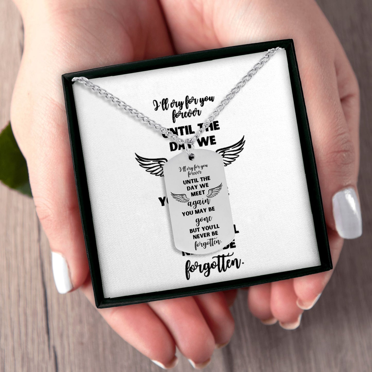 Silver steel memorial dog tag necklace with engraved "I'll cry for you forever" and angel wings in black gift box held by.