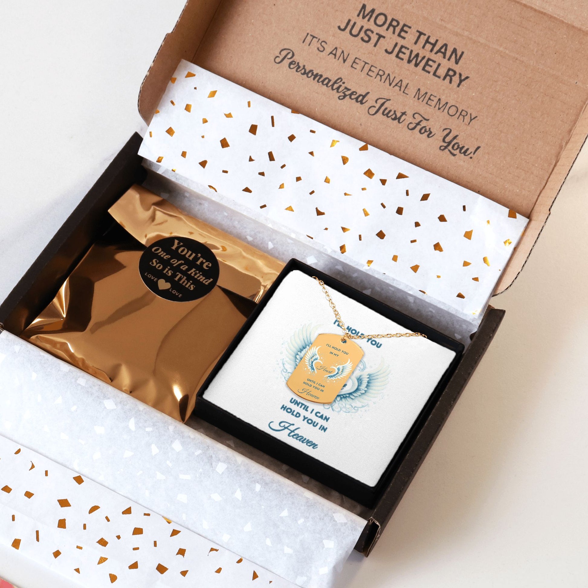 Gold tag necklace with engraved angel wings and elegant chain in a black gift box with gold foil pouch and message card.