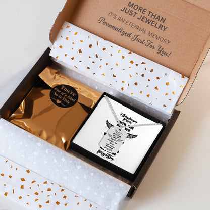 Silver steel memorial dog tag necklace with engraved text in black font inside a gift box with gold and white patterned.