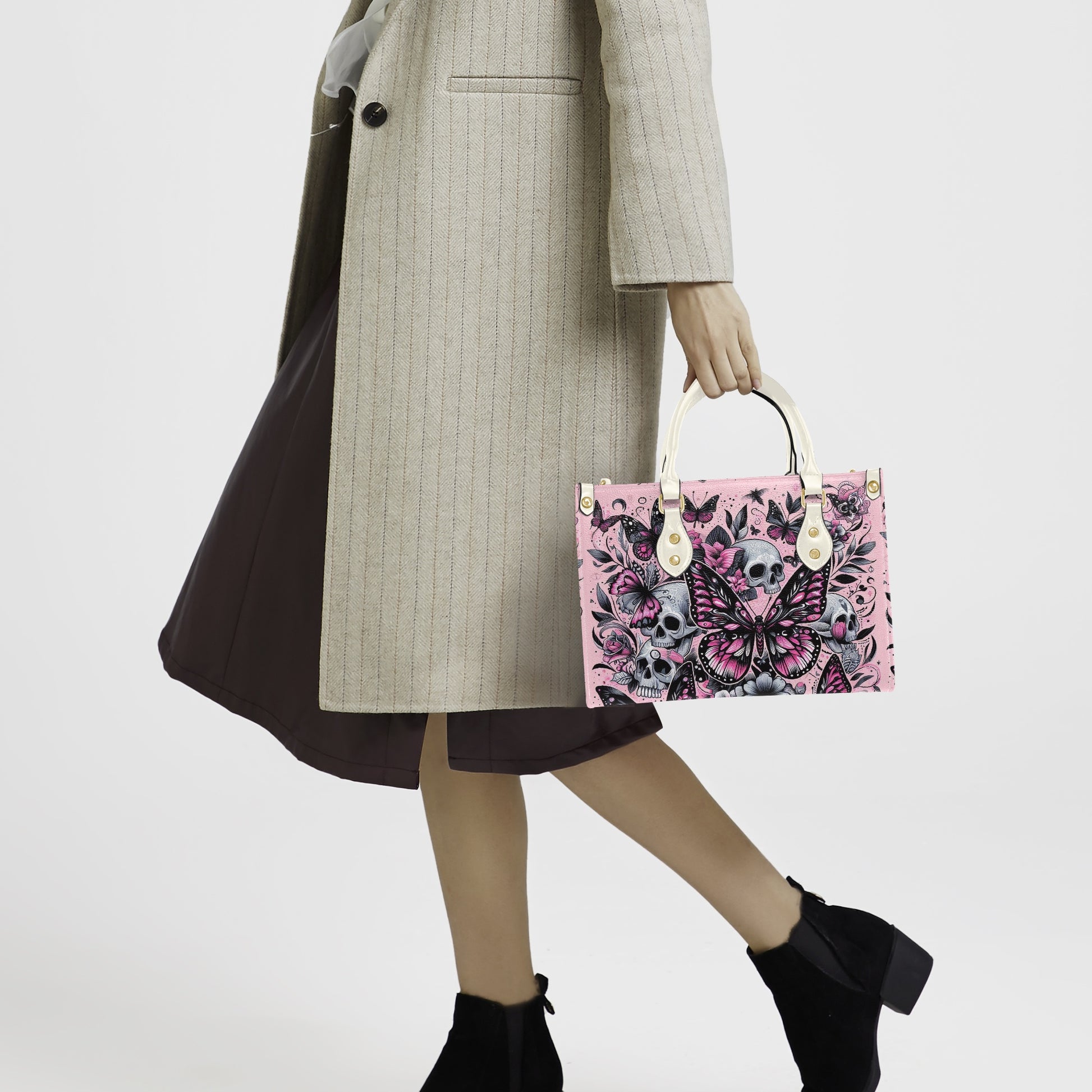 Person holding a pink handbag with floral and skull design against a white background