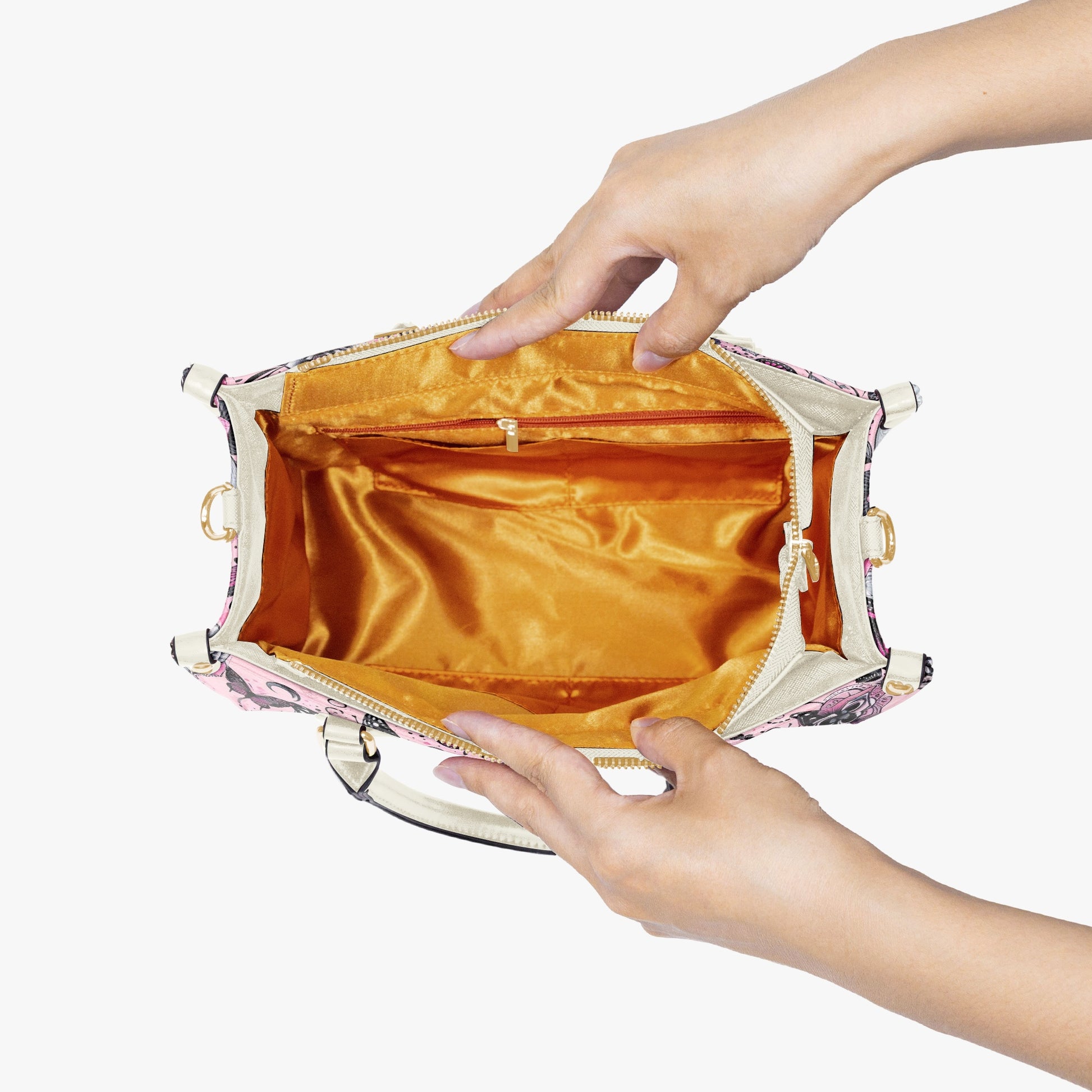 Hand holding a small handbag with a gold interior on a white background