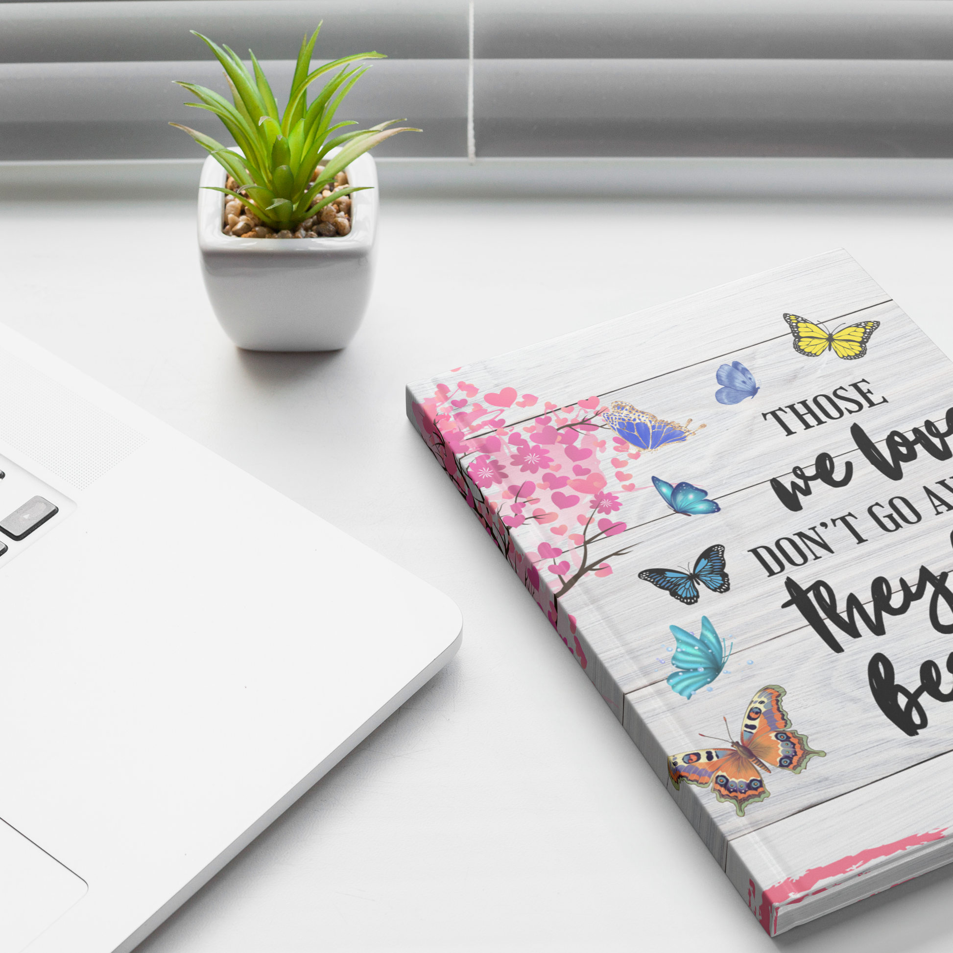 Journal memorial with colorful butterfly and heart designs on a white wooden background cover.