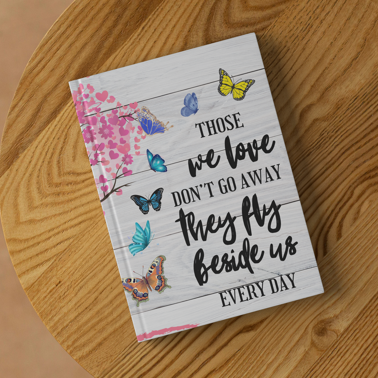 White journal with pink blossom branch and colorful butterflies, black script text saying "Those we love don't go away they.